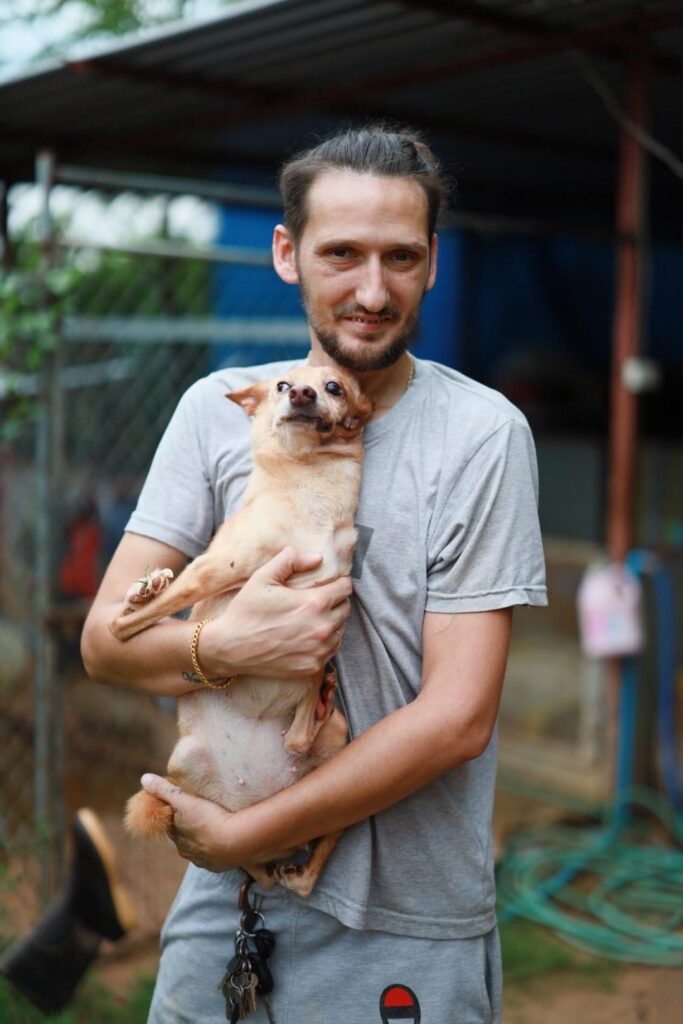 Jessy the handicapped dog being held by volunteer manager Adrian at second chance Thailand